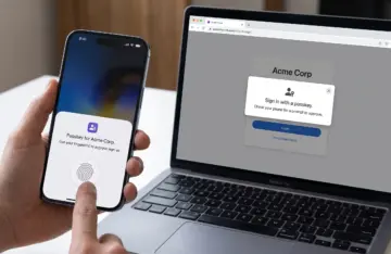 Phone showing a fingerprint prompt to approve a passkey sign-in on a laptop screen